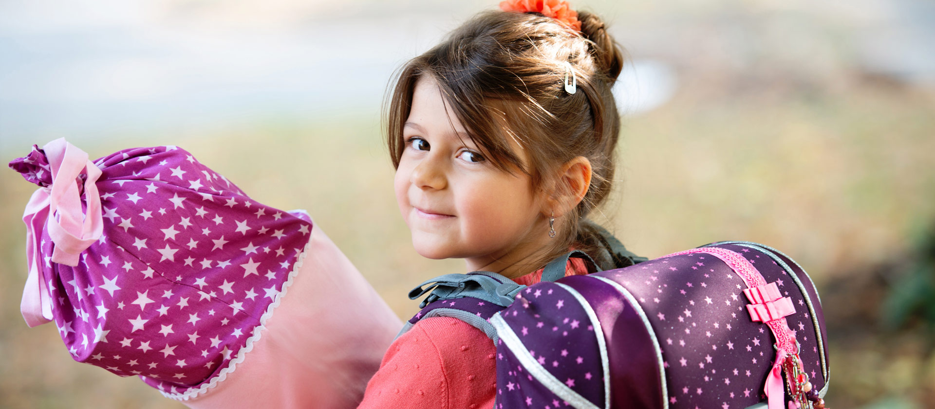 Schulfotografie: Ein Mädchen mit Schultüte und Schulranzen wartet auf die Einschulung