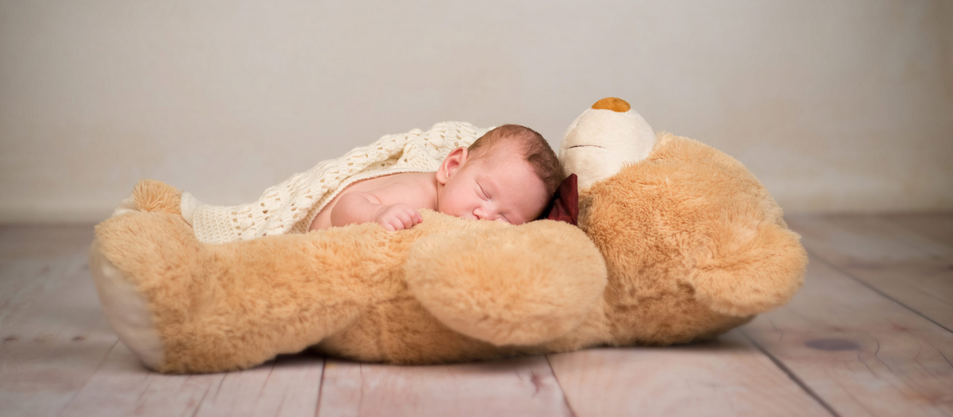 Neugeborenes Baby schläft auf seinem großen Teddy