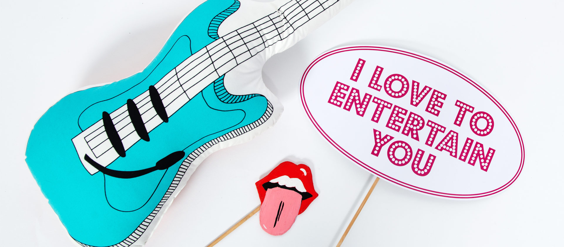 Photobooth-Schild mit der Aufschrift I love to Entertain you, eine Luftgitarre und eine Stones-Zunge an einem Stab 